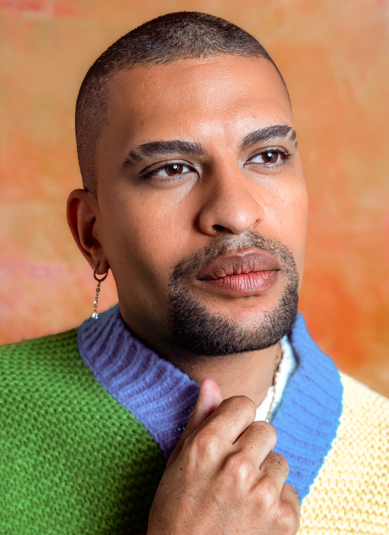 Traidy Naidoo in a colour-blocked knit, looking past the camera.