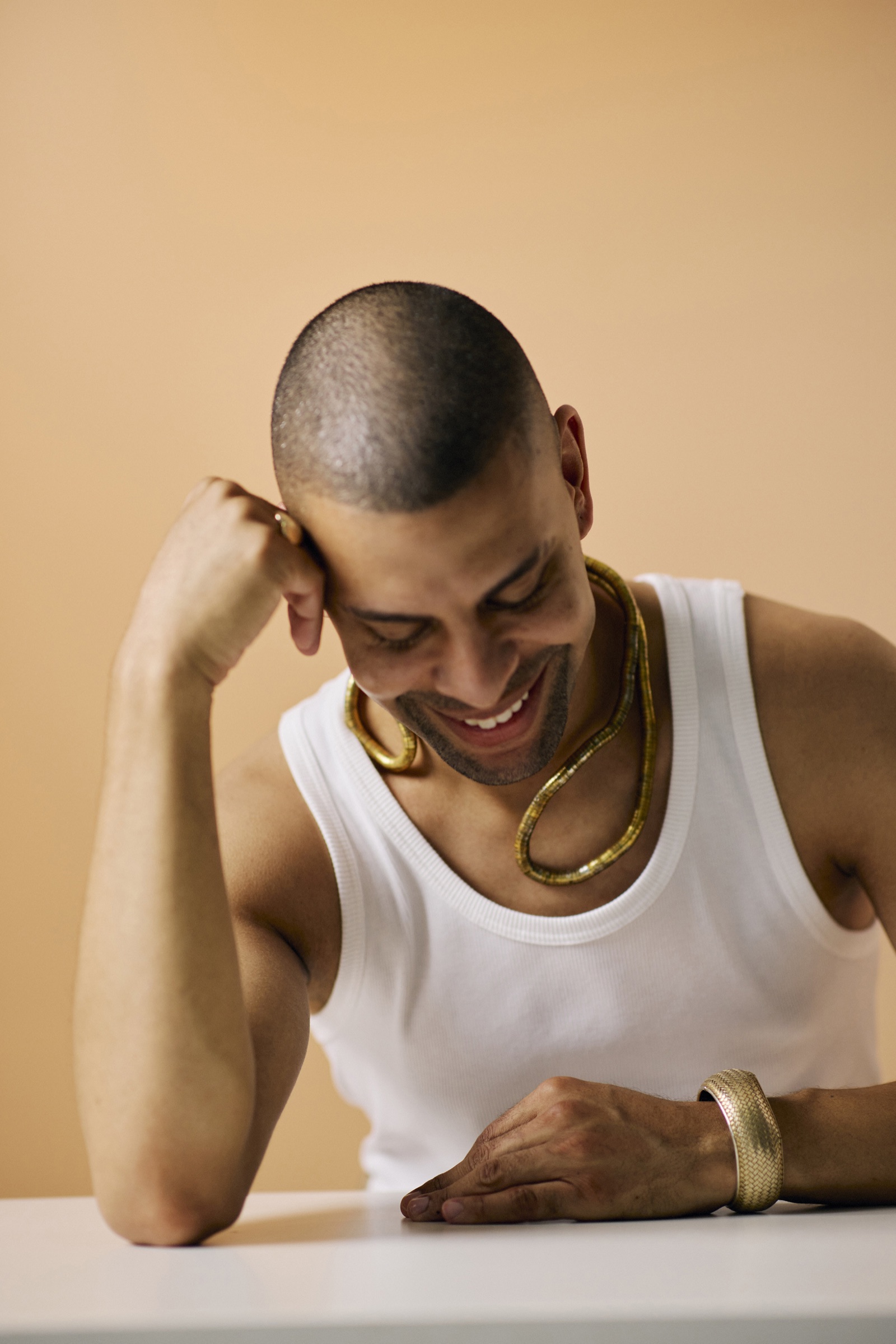 Traidy Naidoo laughing with his head down, resting on a white table.
